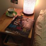 Allison Davis's nightstand: "Lamp, Carmex magazines, glasses, postcard from BFF, 'Whore' teacup/jewelry holder, ring"